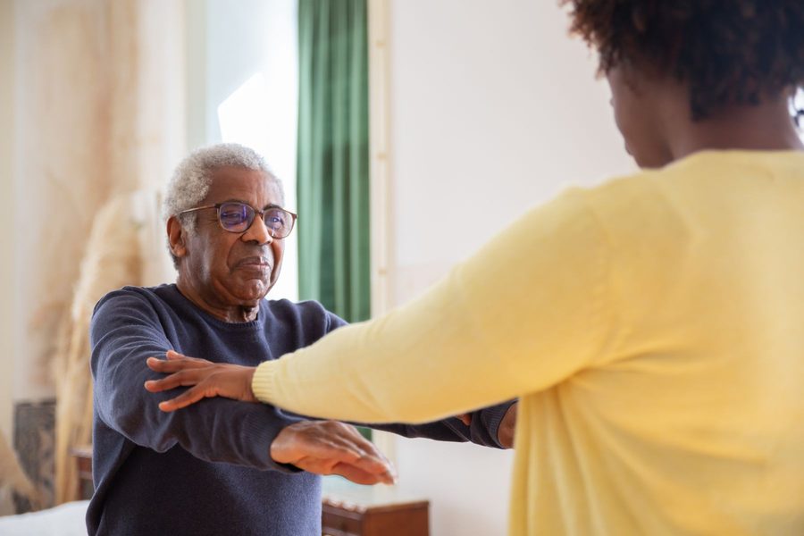 A carer helping a client with the physio exercises his hospital discharge asked for