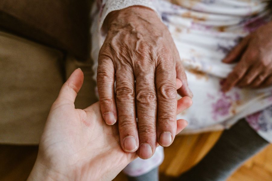 A carer sitting with a client, hands held, during a late-afternoon visit