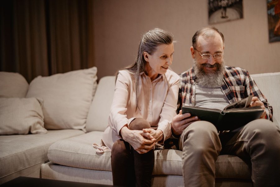 A carer and a woman living with dementia looking through a photo album together